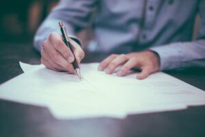 man in shirt writing on documents